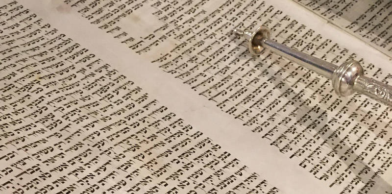Yad pointing to Hebrew writing in a Torah.