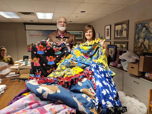 Two Temple members holding up donated blankets for Share the Warmth